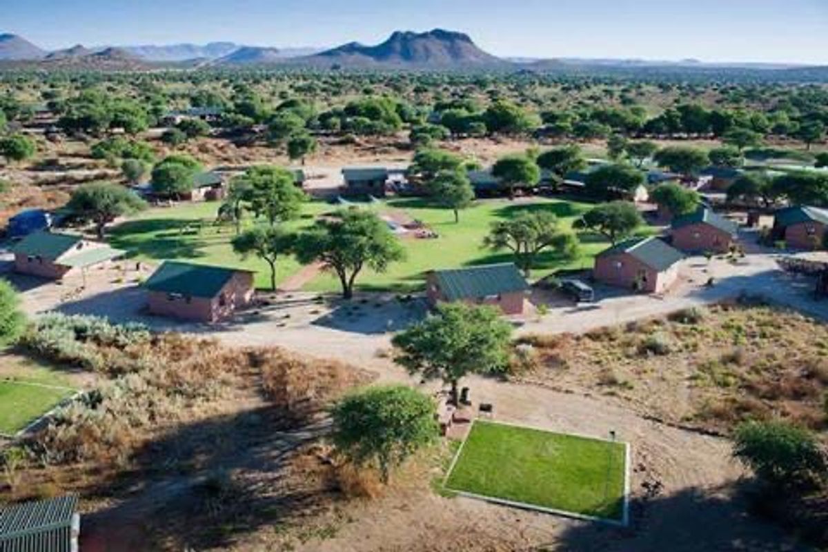 Aerial view of a small holding property featuring multiple detached residential units set within a landscaped garden environment with mountain views.