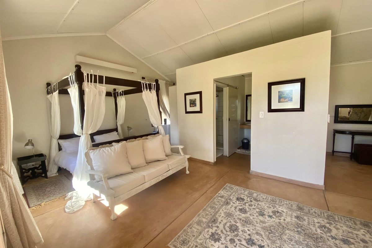 Spacious bedroom featuring vaulted ceilings, polished concrete floors, and direct access to an en-suite bathroom.