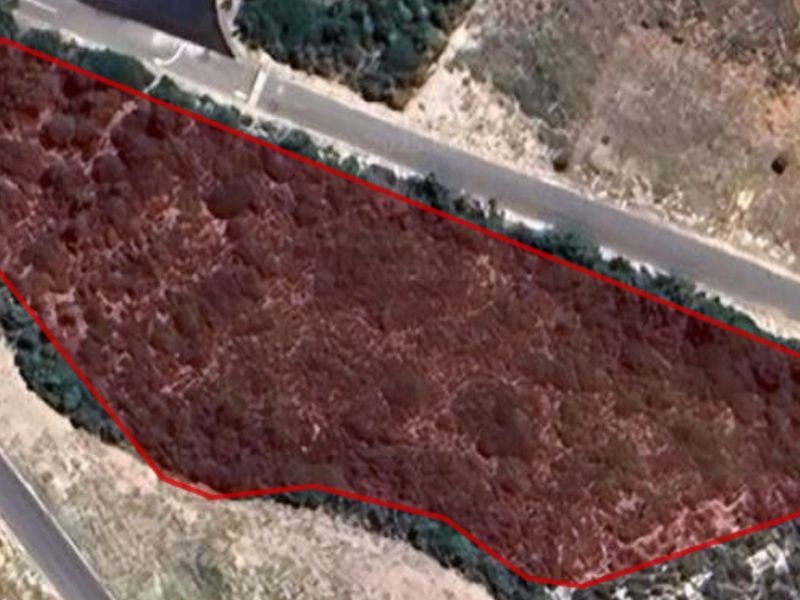 Aerial view of a vacant residential plot of land with natural vegetation, outlined in red for boundary identification.