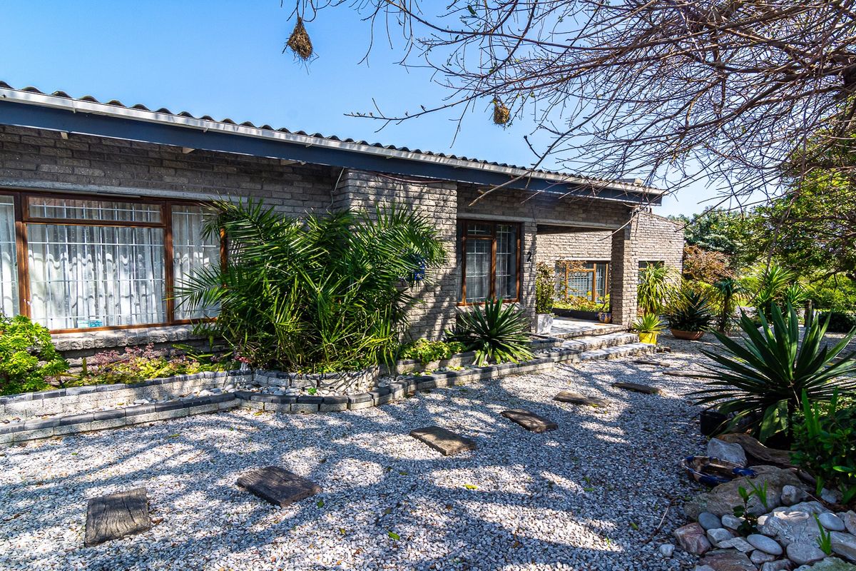 A view of the rear exterior of the house featuring a brick facade, timber window frames, and a landscaped gravel garden area.
