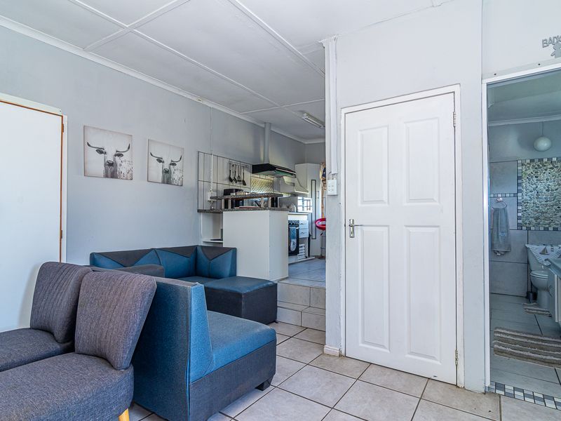 Open plan living area featuring tiled flooring, a raised kitchen section with built-in cabinetry, and direct access to an adjacent bathroom.