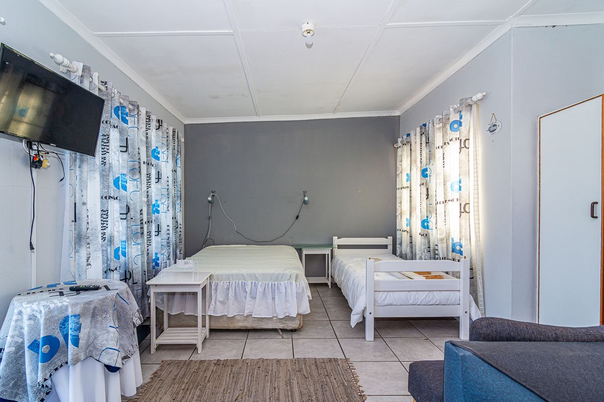 A bedroom featuring tiled flooring and a built-in cupboard, with visible ceiling panel joints and exposed electrical wiring.