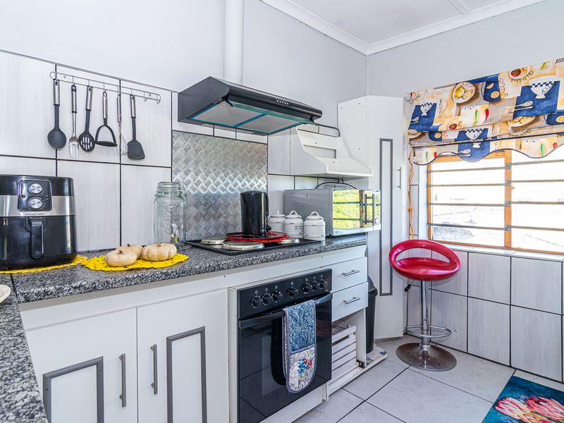 A functional kitchen featuring granite countertops, built-in oven with hob, extractor fan, and tiled splashbacks, offering a practical layout for daily meal preparation.