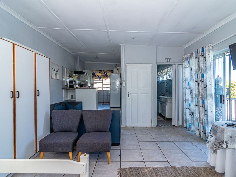 Open plan living area featuring tiled flooring, built-in storage cupboards, and direct access to an outdoor space via a sliding glass door.