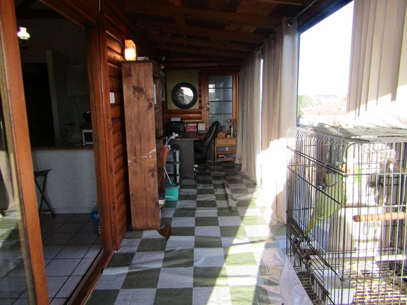 Enclosed patio area featuring timber log walls, wood-paneled ceiling, and tiled flooring, providing a versatile space with direct access to the main living area.
