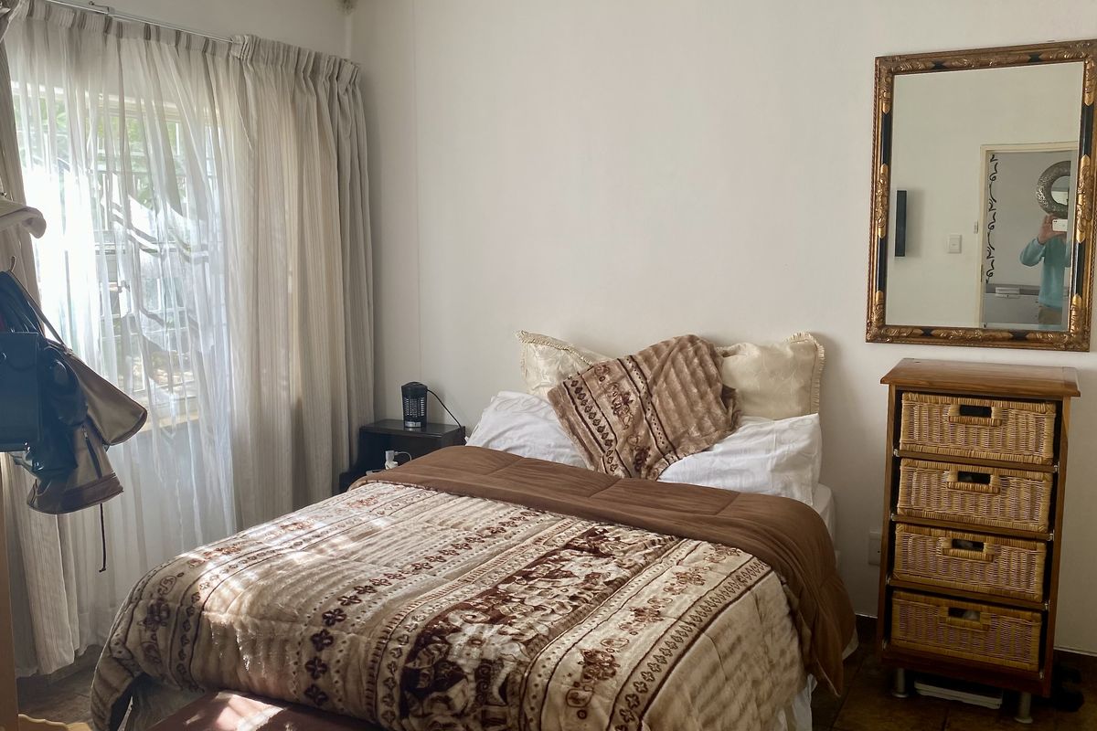 A bedroom featuring tiled flooring and large windows with curtain tracks, providing natural light to the space.