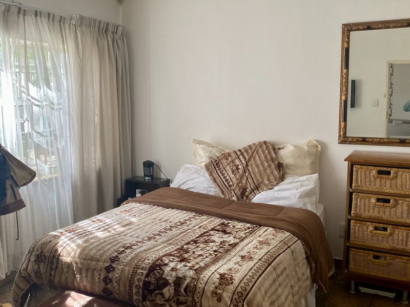 A bedroom featuring tiled flooring and large windows with curtain tracks, providing natural light to the space.