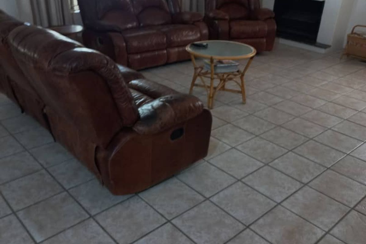 Spacious living room featuring ceramic floor tiles and a built-in fireplace, offering a comfortable and functional area for relaxation.