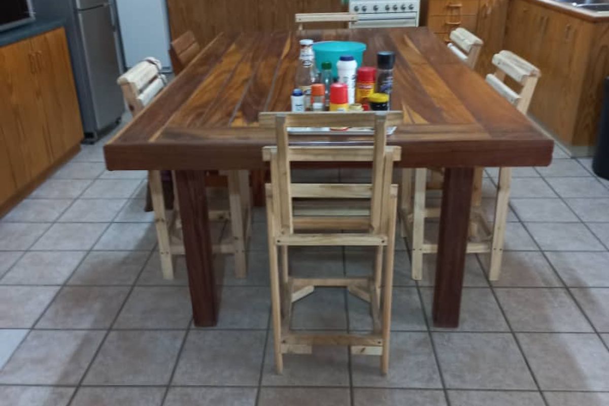 A functional kitchen featuring wooden cabinetry, tiled backsplash, and tiled flooring, providing a practical workspace with a central dining area.