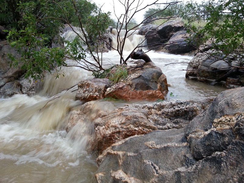 A scenic view of a natural stream flowing over rock formations within the property grounds.
