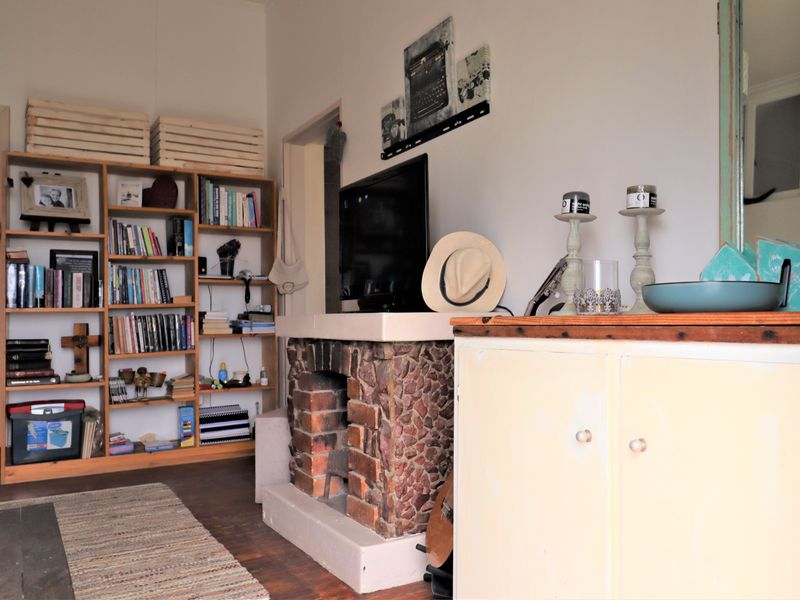 A cozy living room featuring a rustic stone fireplace, built-in wooden shelving, and warm timber flooring.