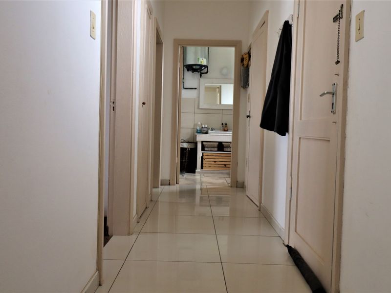 A functional hallway with tiled flooring and multiple internal doors, providing access to various rooms including a bathroom visible at the end.