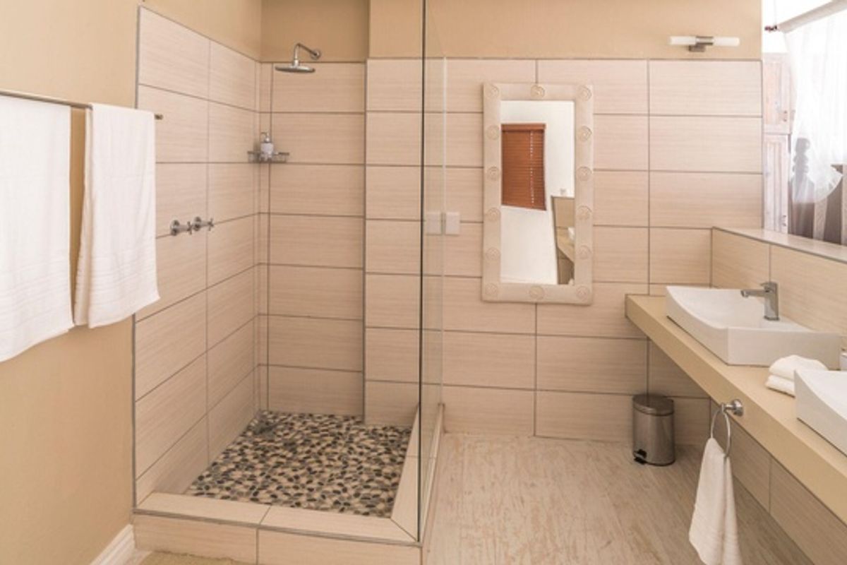 Modern bathroom featuring a walk-in shower with pebble flooring, glass enclosure, and a double vanity with vessel sinks.