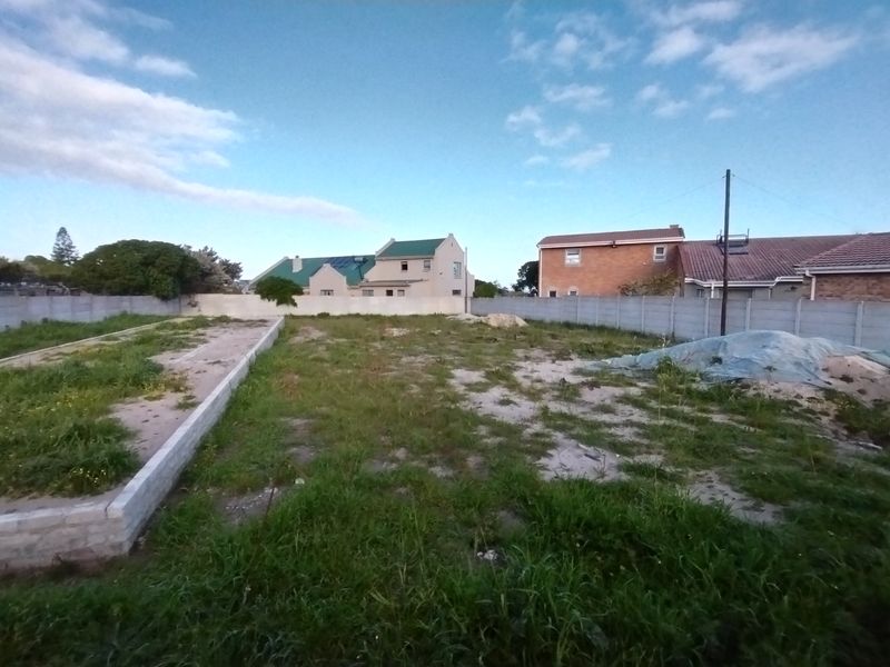Vacant residential plot featuring a concrete foundation slab, perimeter precast walling, and surrounding residential development.