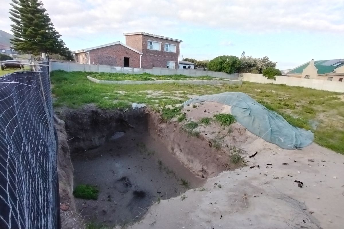 Vacant residential land featuring an open excavation pit and boundary walling, situated in a developed neighborhood.