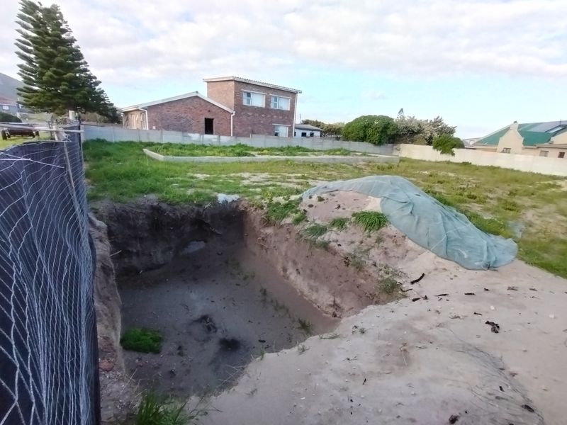 Vacant residential land featuring an open excavation pit and boundary walling, situated in a developed neighborhood.