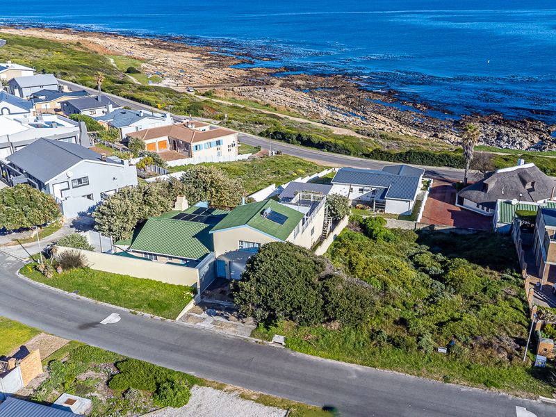 Aerial view of a residential property situated in a coastal neighborhood, showcasing proximity to the ocean and surrounding street infrastructure.