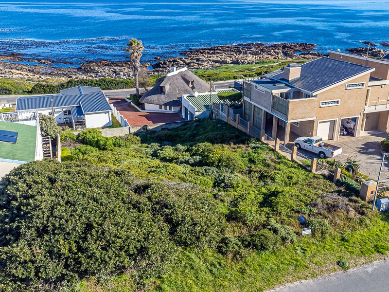 Aerial view of a vacant residential plot situated in a coastal neighborhood, offering proximity to the ocean and surrounding established homes.