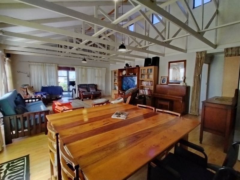Spacious open-plan living and dining area featuring high vaulted ceilings with exposed timber trusses and warm timber flooring throughout.