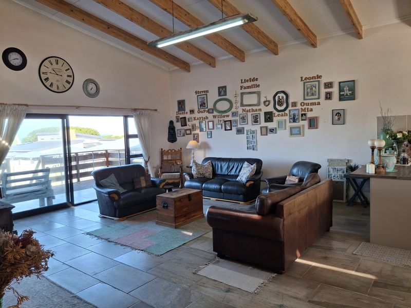 Spacious open-plan living area featuring vaulted ceilings with exposed timber beams, tiled flooring, and large sliding glass doors leading to an outdoor space.