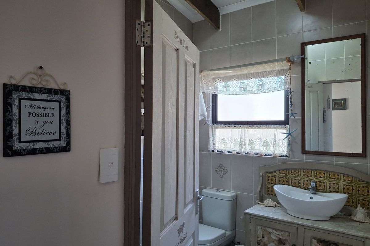 A functional bathroom featuring a vessel sink on a vanity cabinet, tiled walls, and a toilet, with a classic timber ceiling beam detail.