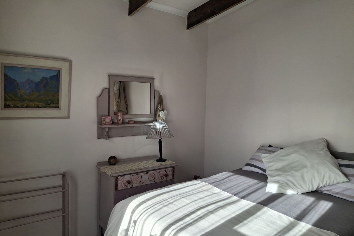 A cozy bedroom featuring exposed timber ceiling beams and neutral wall finishes, offering a comfortable and characterful living space.