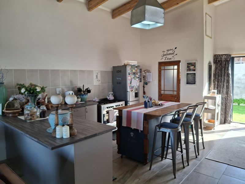 A kitchen featuring exposed timber ceiling beams, tiled flooring, a tiled backsplash, and a freestanding gas stove with a central island workspace.