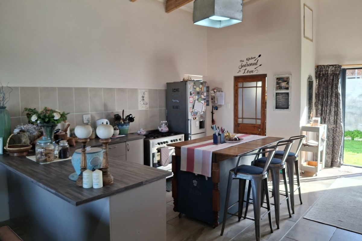 A kitchen featuring exposed timber ceiling beams, tiled flooring, a tiled backsplash, and a freestanding gas stove with a central island workspace.