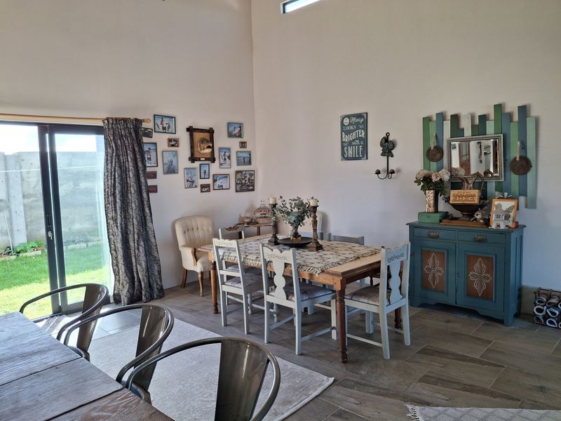A spacious dining area featuring tiled flooring, high ceilings, and a large sliding glass door providing direct access to the garden.