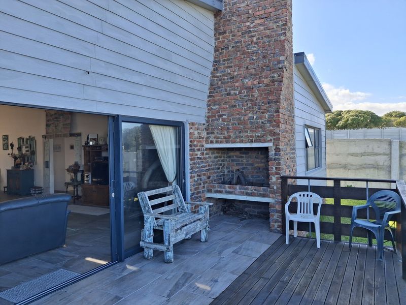 Outdoor patio area featuring a built-in brick fireplace, timber decking, and sliding glass doors providing seamless access to the interior living space.