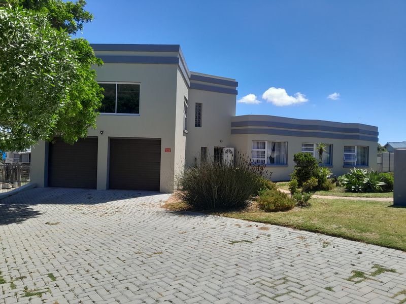 Front elevation of a modern double-story house featuring a paved driveway, double garage, and established garden.