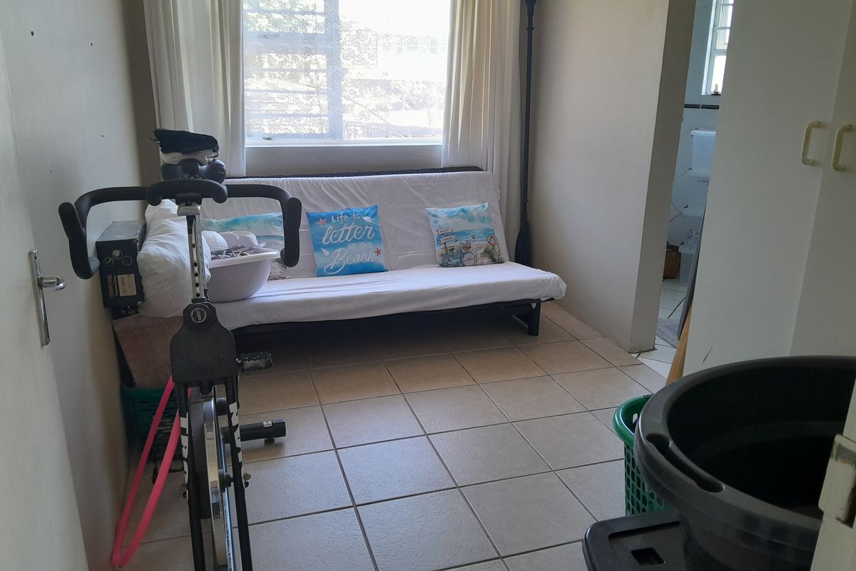 A functional bedroom space featuring tiled flooring and a window, with an adjacent bathroom area visible.