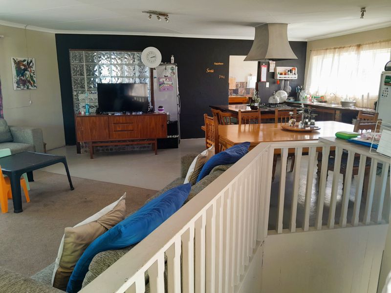 Spacious open-plan living and kitchen area featuring a glass block feature wall, functional kitchen layout, and staircase access.
