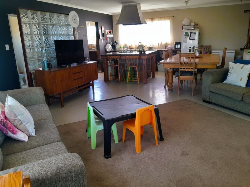 Spacious open-plan living and kitchen area featuring a central island with gas hob, extractor fan, and a decorative glass block partition.