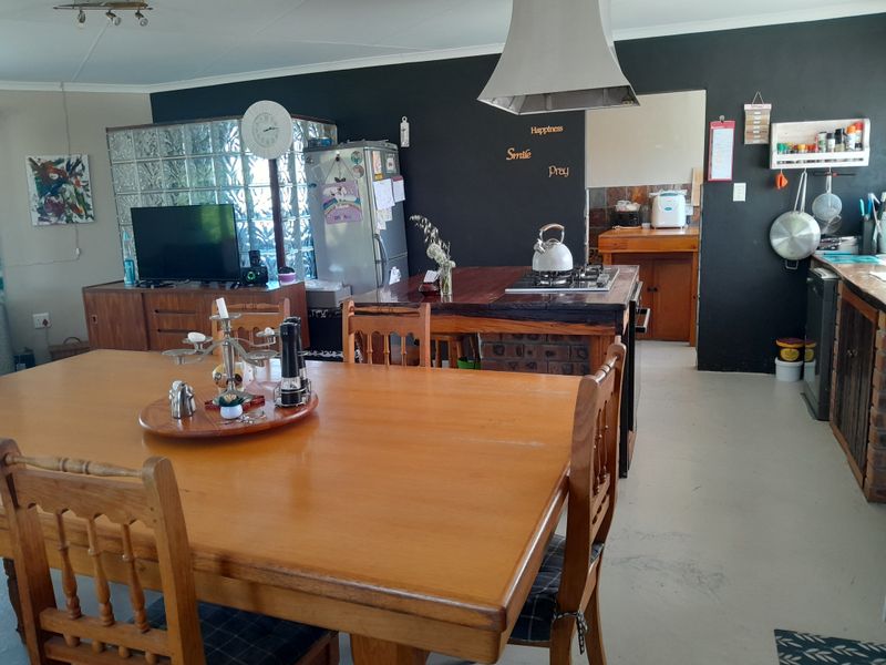 Open-plan kitchen and dining area featuring a central island with gas hob, extractor fan, and a distinctive glass block feature wall.