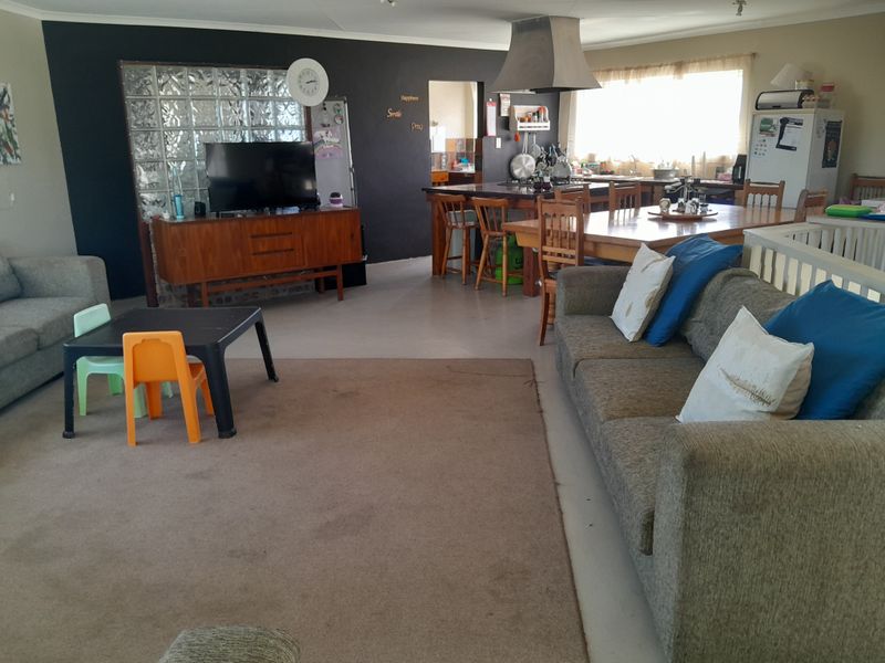 Spacious open-plan living and kitchen area featuring a glass block wall, central kitchen island, and stainless steel extractor fan.