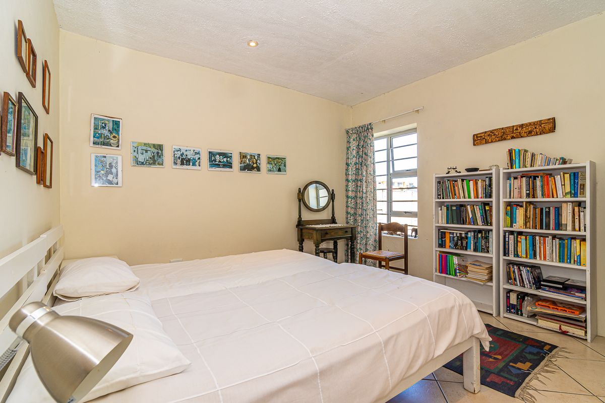 A functional bedroom featuring tiled flooring, recessed ceiling lighting, and a metal-framed window, providing a comfortable and well-lit living space.