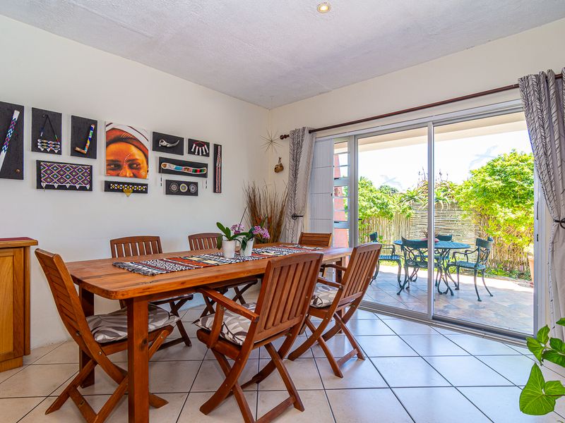 Bright dining room featuring tiled flooring and large sliding glass doors that provide seamless access to the outdoor patio area.