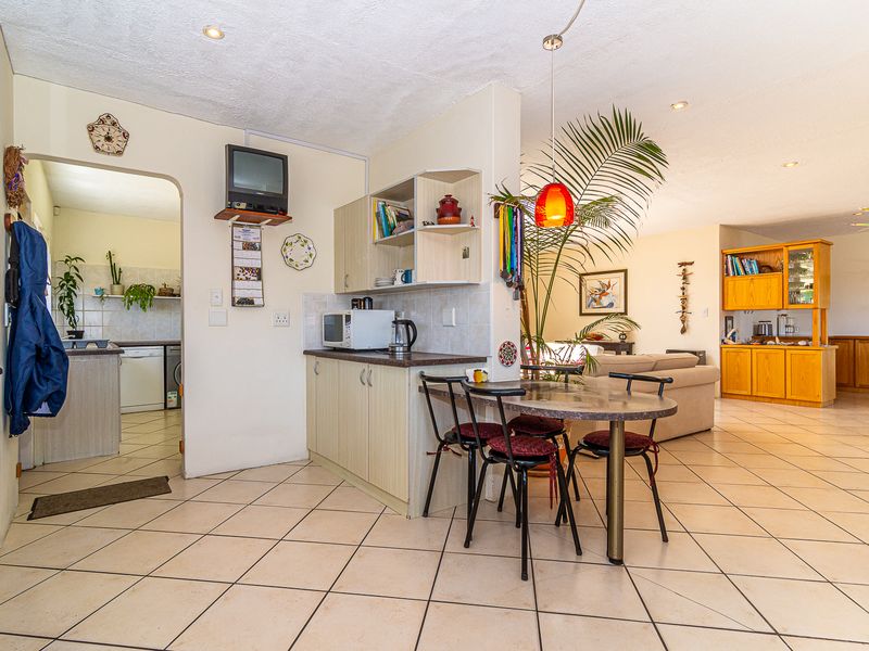 Open plan living and dining area featuring tiled flooring, built-in cabinetry, and an archway leading to a secondary kitchen or utility space.