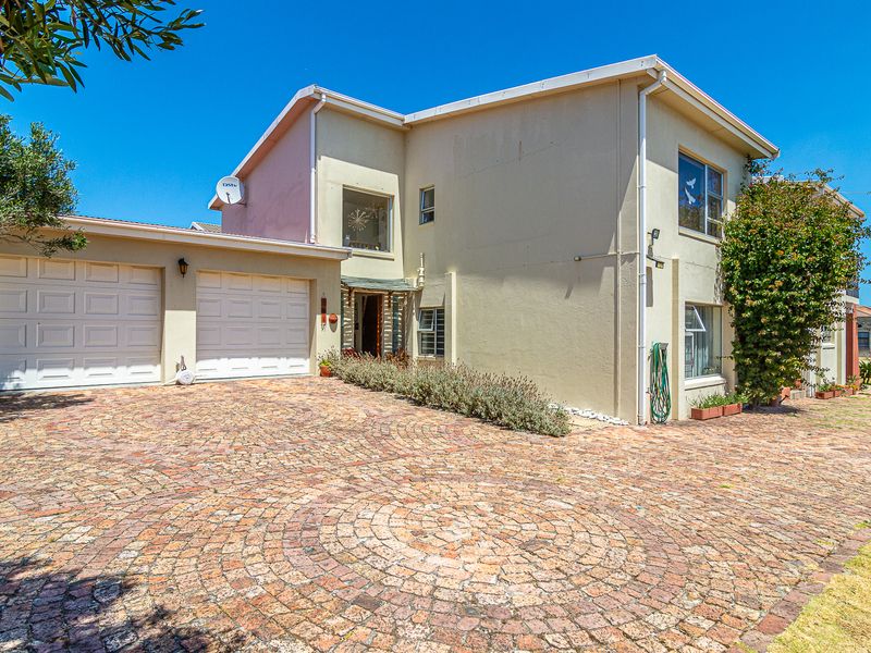 Front elevation of a double-story house featuring a double garage, paved driveway, and established garden elements.
