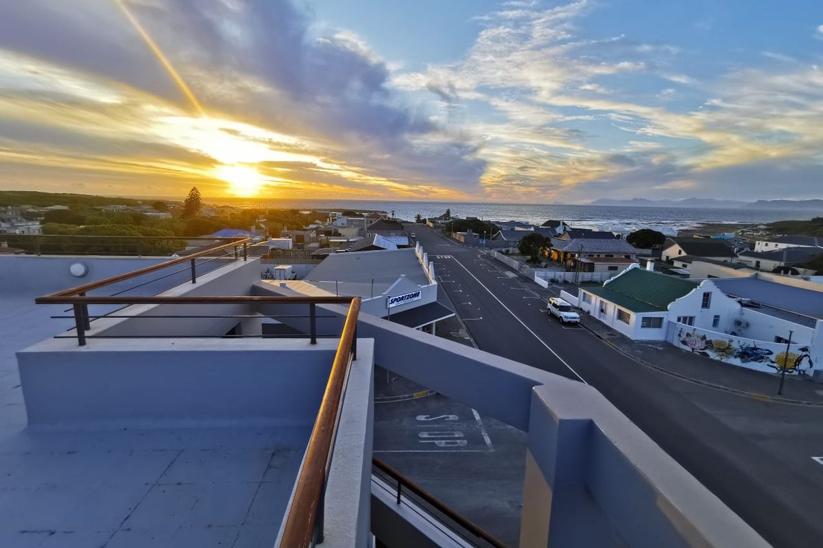Elevated view from a balcony overlooking the coastal town and ocean at sunset.