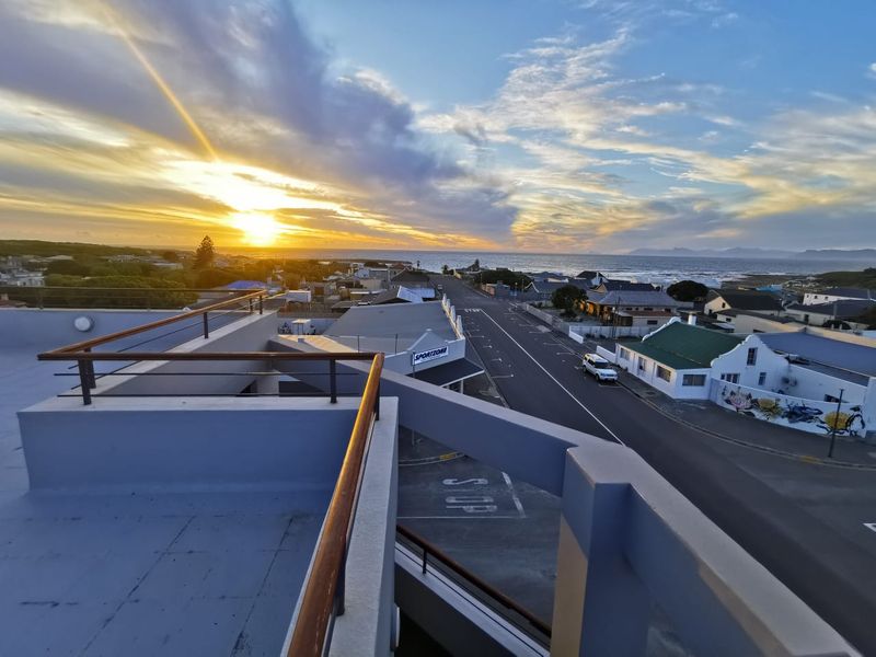 Elevated view from a balcony overlooking the coastal town and ocean at sunset.