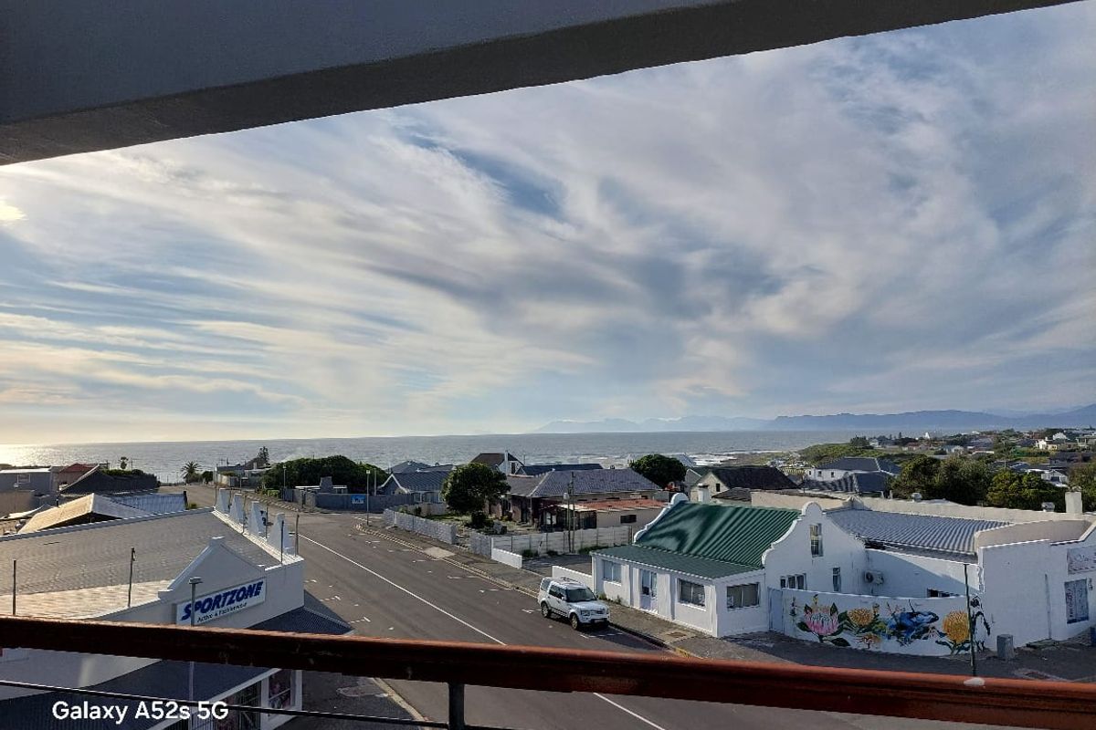 Elevated coastal view overlooking the surrounding neighbourhood, street, and distant ocean horizon from a balcony.