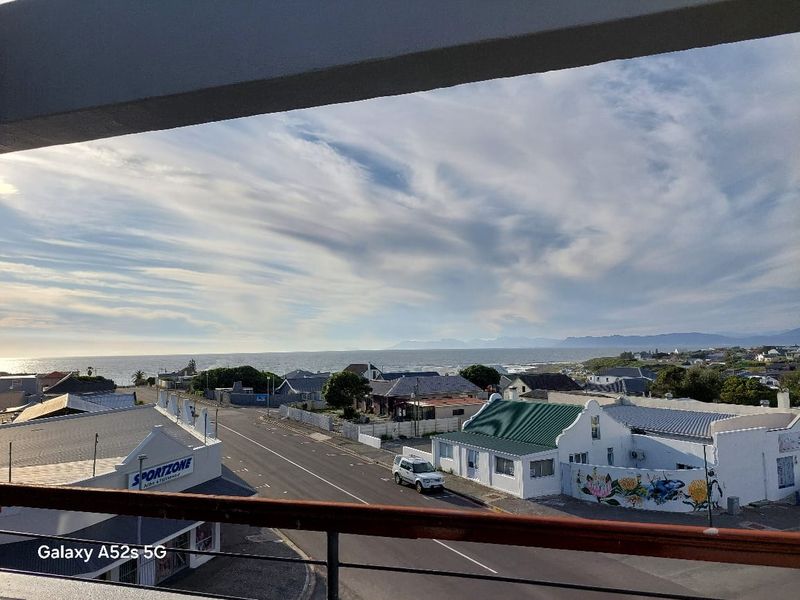 Elevated coastal view overlooking the surrounding neighbourhood, street, and distant ocean horizon from a balcony.