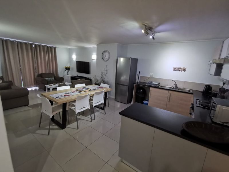 Spacious open-plan living area featuring a modern kitchen with laminate countertops, tiled flooring, and seamless flow to the dining and lounge space.