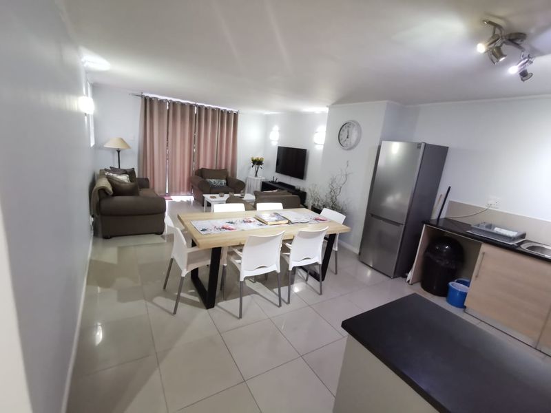 Open-plan living area featuring a modern kitchen with sleek cabinetry, tiled flooring, and a seamless flow into the dining and lounge space.