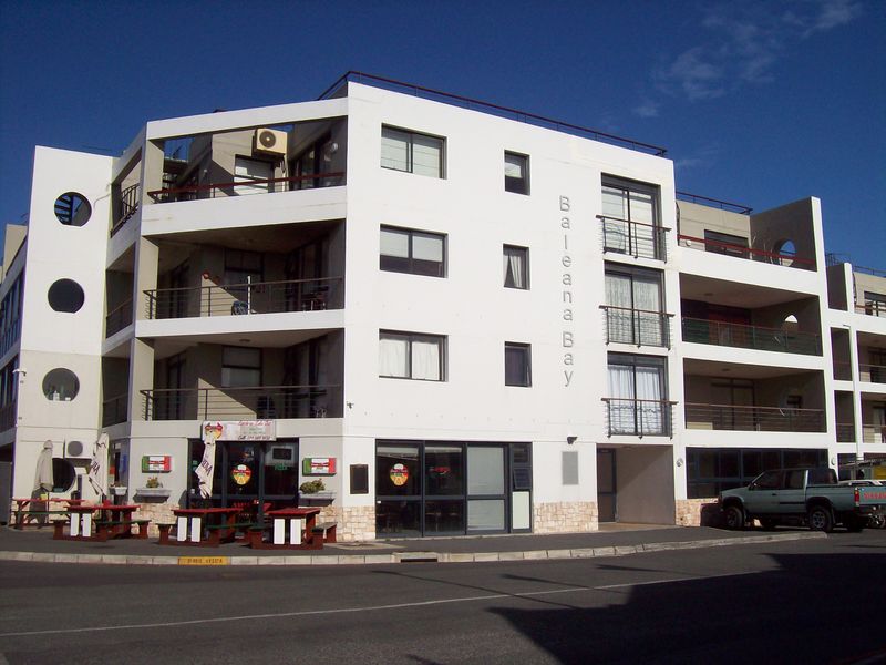 Exterior view of Baleana Bay apartment complex featuring multi-level balconies, stone base detailing, and ground floor commercial frontage.