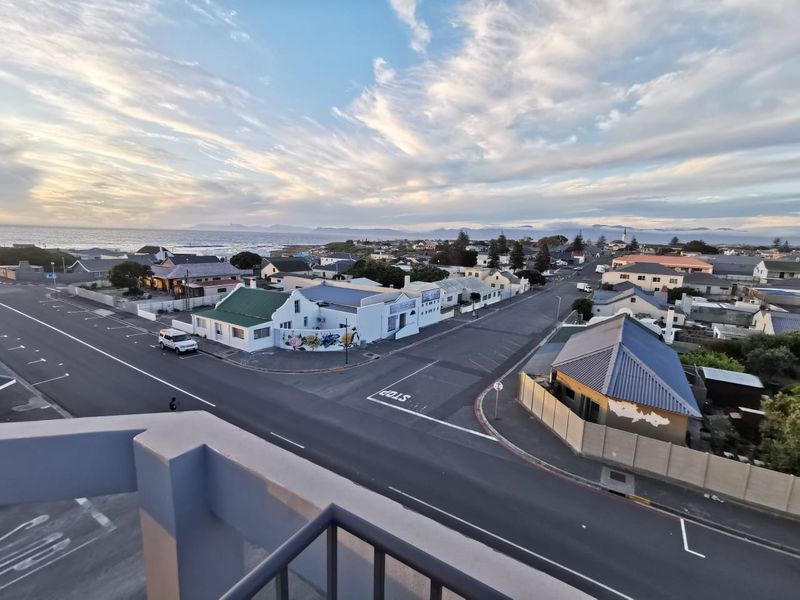 Elevated panoramic view overlooking the surrounding coastal neighborhood, streets, and distant mountain range from a balcony vantage point.