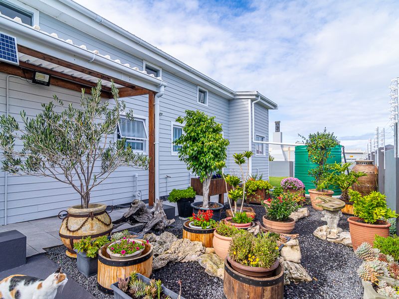 A well-maintained rear exterior area featuring a timber pergola, solar panel installation, and a landscaped garden with gravel and potted plants.