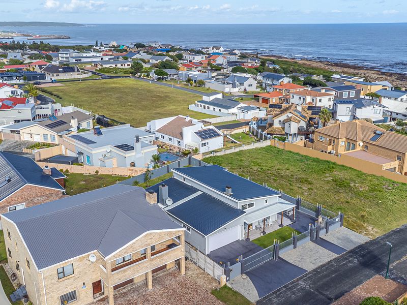 An aerial view of the residential property showing the roof structure, driveway, and surrounding coastal neighborhood landscape.